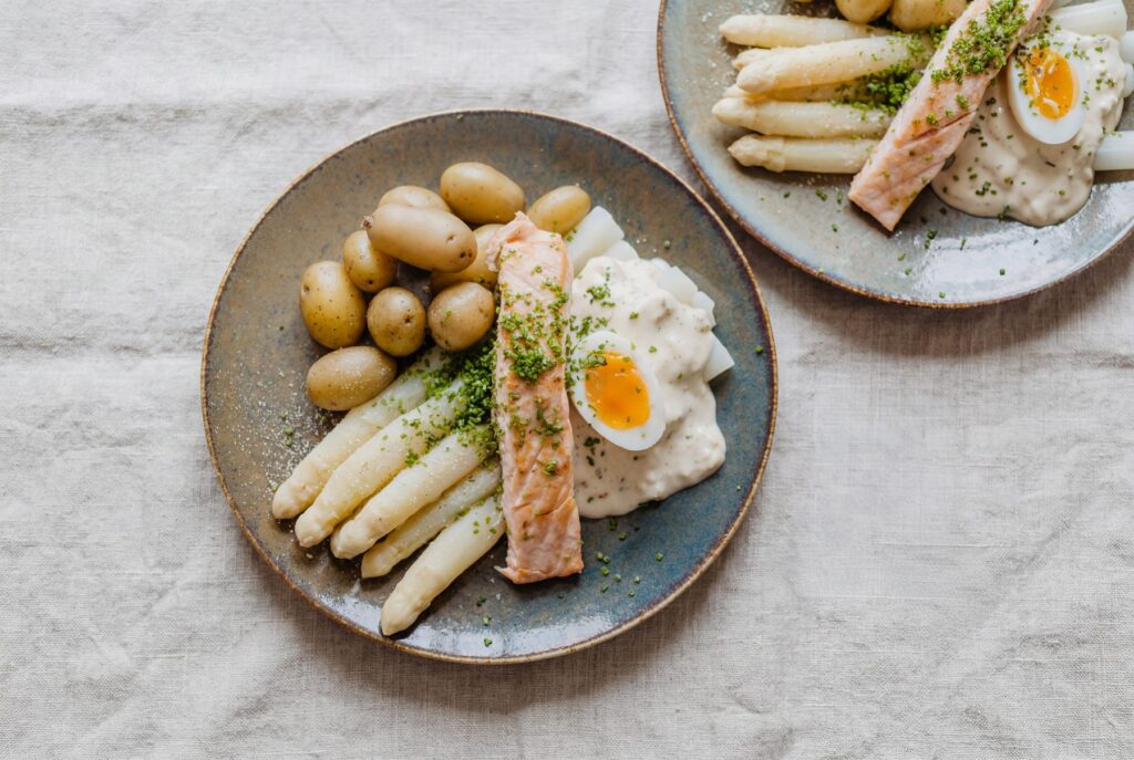 Bord met witte asperges, zalm, krieltjes en gekookt ei op een linnen tafelkleed